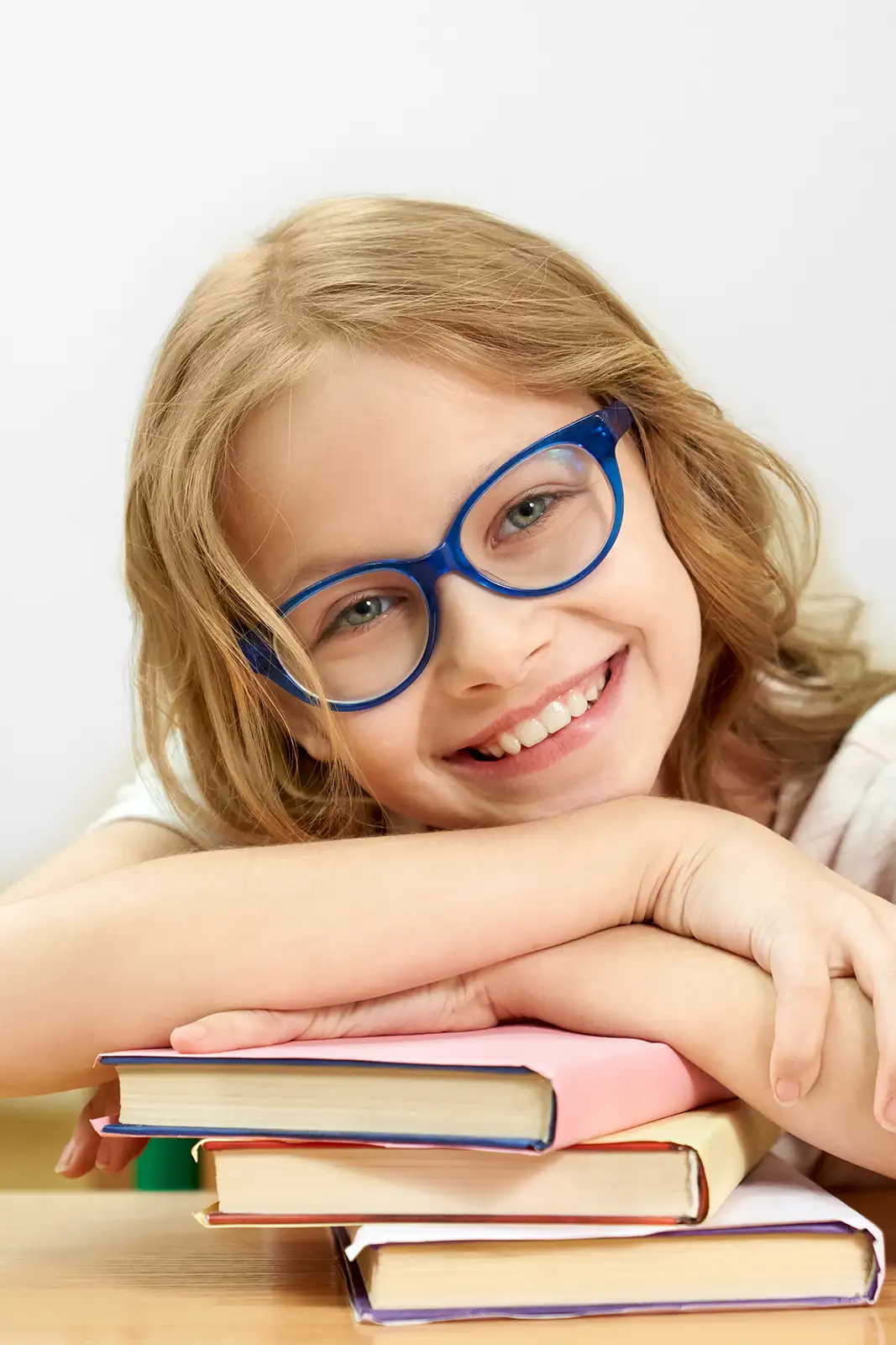 Kind in der Schule mit auffälliger blauer Brille lächelt in die Kamera