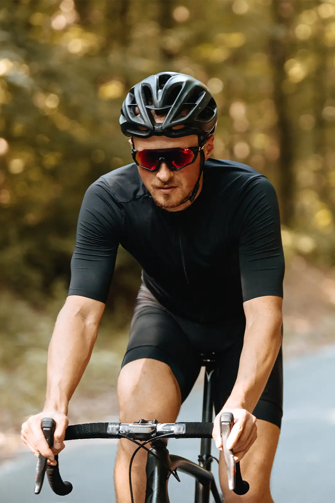 Rennradfahrer fährt Fahrrad und trägt eine Sportbrille mit verspiegelten Gläsern.