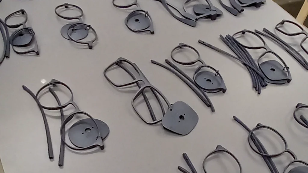 Mehrere 3D-gedruckte Brillenfassungen und Einzelteile auf einem Tisch